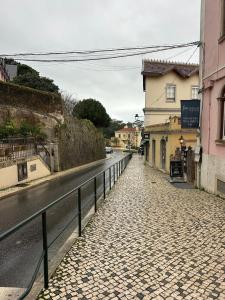 a cobblestone street next to a road with buildings at Sintra Flower Camelia Apartment in Sintra
