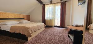 a hotel room with a bed and a window at Vila Dascalita in Moieciu de Sus