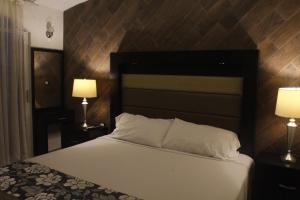 a bedroom with a bed with a black headboard and two lamps at Villas Tecuanapan in Xalapa