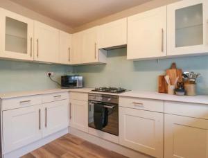 a kitchen with white cabinets and a stove at High Tide in Whitstable
