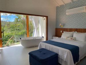 a bedroom with a bed and a tub and a window at Chalés Colina dos Colibris in Santa Teresa