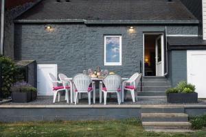 a table and chairs in front of a house at Au Chant des Roches Gîte en pierre avec jardin à Cerfontaine in Cerfontaine