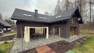 a black house with a patio and a table at Apartament Cisza Leśna in Gołubie