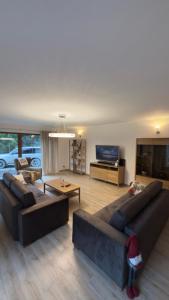 a living room with two couches and a flat screen tv at Apartament Cisza Leśna in Gołubie