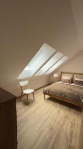 a bedroom with a bed and a chair and a skylight at Apartament Cisza Leśna in Gołubie