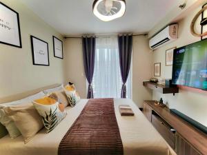 a bedroom with a large bed with a flat screen tv at Welcome to Cozy Staycation in Suba