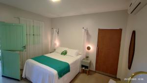 a bedroom with a white bed with a green blanket at Casa das Flores Bistrô e Pousada in Taquarussu Tocantins