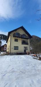 a large house with snow in front of it at Vila Dascalita in Moieciu de Sus