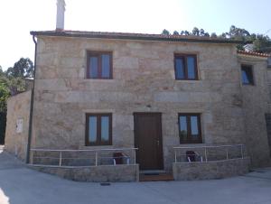 a stone building with a brown door and windows at Eira de Mantoño in Mantoño