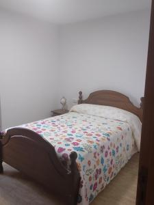 a bedroom with a bed with a flowered blanket on it at Eira de Mantoño in Mantoño