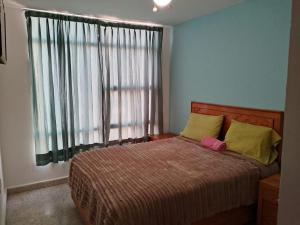 a bedroom with a bed with a large window at Hotel Mi Casa Mata II in Morelia