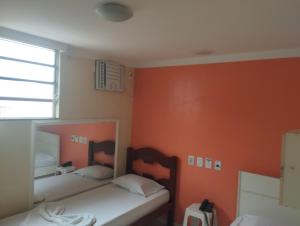 two beds in a room with orange walls at Motel pousada Zafira in Salvador