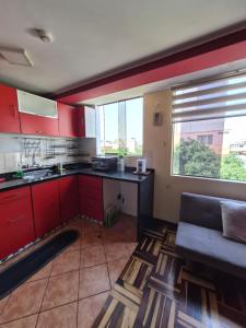 a kitchen with red cabinets and a couch in a room at Apartamento Acogedor, tranquilo y privado in Lima +34 photos