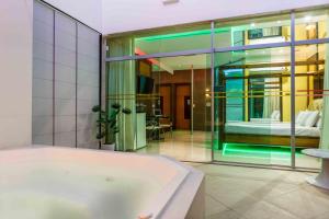 a bathroom with a bath tub and a bedroom at Status Motel in Serra