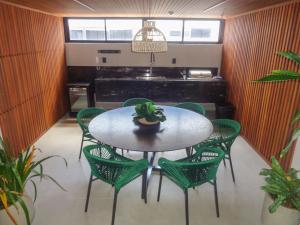 a table with green chairs and a potted plant on it at Flat Hit Cabo Branco in João Pessoa