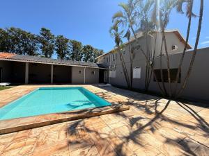 a swimming pool in front of a house with palm trees at Hotel Nova Sorocabana in Brodósqui