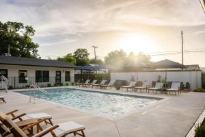 a swimming pool with chairs and tables and the sun at Gloria Inn - Unit 8 in Waco
