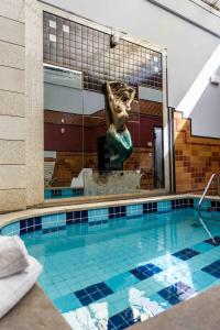 a swimming pool with a statue in the middle of it at Status Motel in Serra