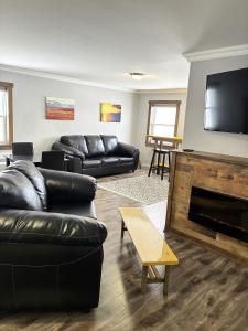 a living room with black leather furniture and a flat screen tv at Augustus Jane Inn in Rocky Harbour