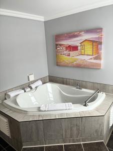 a bath tub in a bathroom with a painting on the wall at Augustus Jane Inn in Rocky Harbour +27 photos