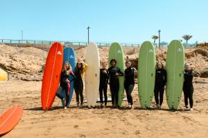 a group of people holding their surfboards on the beach at Catamaran Surf House in Agadir nʼ Aït Sa
