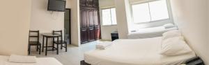 a hotel room with two beds and a table and chairs at Hotel CATAYAR in Santa Marta