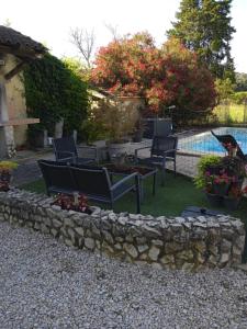 a yard with chairs and a stone wall and a pool at La barque aux Romarins in Orange +10 photos