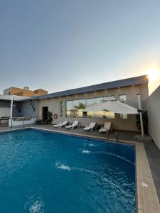 a swimming pool with chairs and an umbrella next to a building at IN 2 Chalet in Jeddah