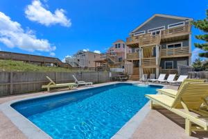 a swimming pool with chairs and a house at 7081 - Southern Breeze in Nags Head