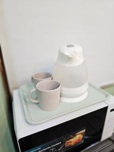 a microwave with two cups and a blender on a shelf at Green Zen Studio Metro 15 mins walk away in Dubai