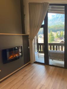 a living room with a fireplace and a sliding glass door at Marova Luxury Loft Caraiman View in Buşteni