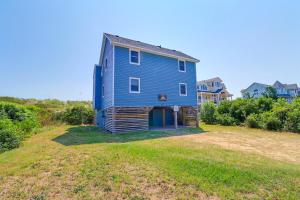 a blue house sitting on top of a grass field at 1245 - Castle Sween in Corolla +39 photos