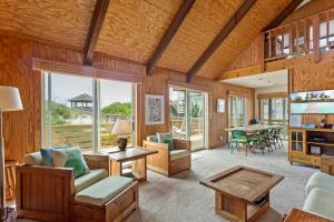a living room with wood paneling and a large window at 1245 - Castle Sween in Corolla