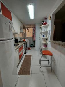 a kitchen with a refrigerator and a chair in it at Diamante guarapari in Guarapari +1 photo