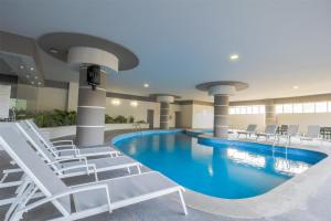 a swimming pool in a hotel with lounge chairs and a pool at Best Western Plus Santa Cecilia Pachuca in Pachuca de Soto