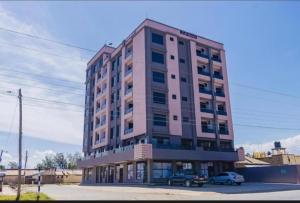 a tall pink building with a car parked in front of it at Silvia Homes Nanyuki in Nanyuki