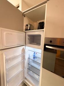 an empty refrigerator with its door open in a kitchen at Riviera Begonia Appartement - Parking Privé in Roquebrune-Cap-Martin