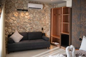 a living room with a couch and a stone wall at Alkioni Boutique Hotel in Pýli