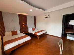 a hotel room with two beds and a table at Hotel Wilson Upala in Upala