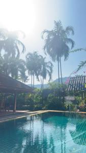 a swimming pool with palm trees in the background at Watermelon House at Nong Thale Garden & Kitchen in Ban Khao Klom