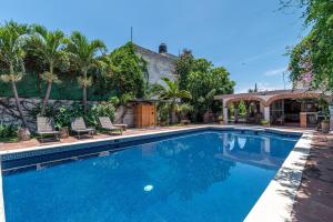 a swimming pool with two chairs and a house at Quinta Rustica "La Aguacana" in Cuautla Morelos