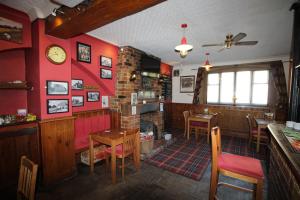 a restaurant with red walls and tables and a fireplace at The Clothiers Arms in Stroud