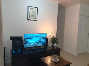 a living room with a flat screen tv and a table at Dwellers Double in Grassy Park