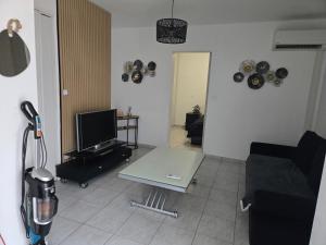 a living room with a couch and a table and a tv at Le cocon de mag in Miramas