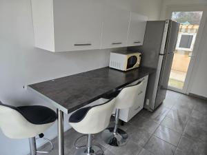 a kitchen with a counter with two chairs and a microwave at Le cocon de mag in Miramas