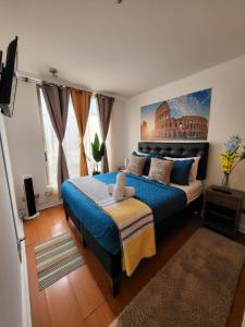 a bedroom with a large bed with a blue bedspread at Living Suite in El Cerrillo