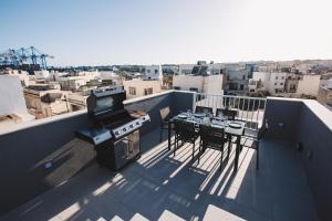 a balcony with a grill and a table and chairs at Seaside Luxury Home with Rooftop Pool in Birżebbuġa