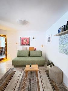 a living room with a green couch and a table at Triglav NP Apartment - above Bled in Zgornje Gorje