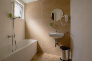 a bathroom with a tub and a sink and a mirror at Le Bistro in Valkenburg