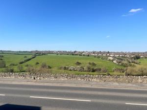 a road with a fence on the side of a field at Upper Valley View in Keynsham +4 photos